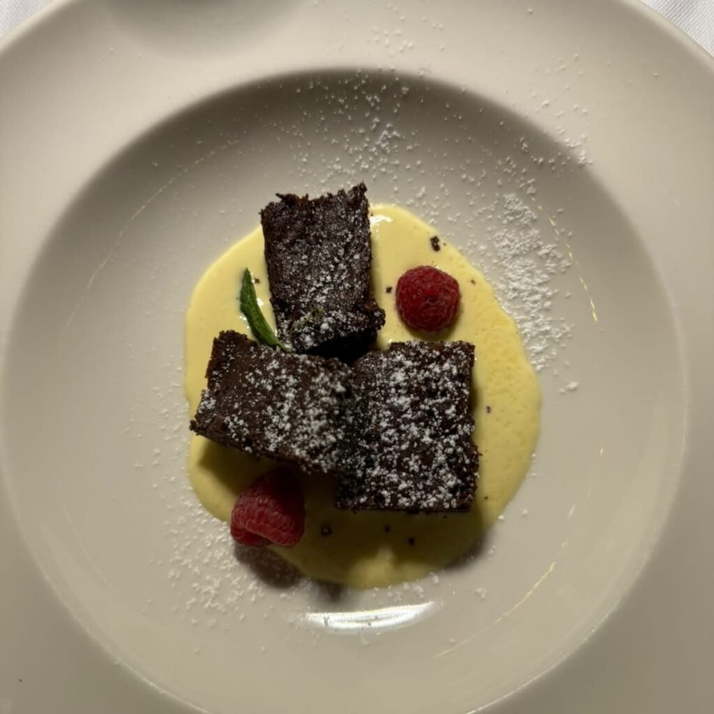 Quadrotti di torta al cioccolato fondente con crema inglese alla vaniglia e lamponi freschi del Ristorante momi